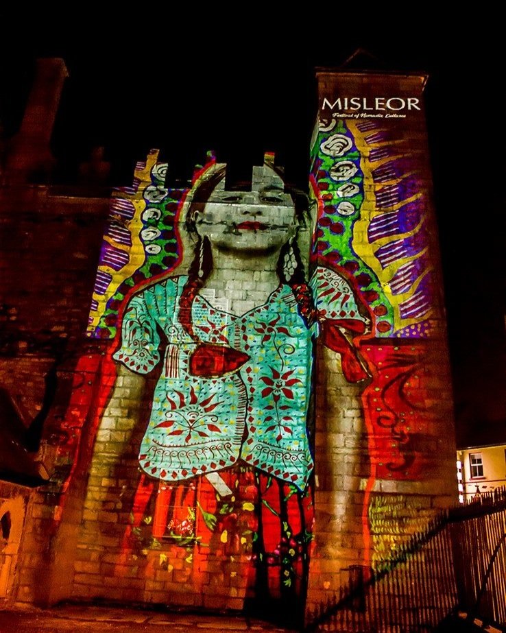 Misleór Festival outdoor visual projection on a stone building of a nomadic person in brightly coloured cultural clothing