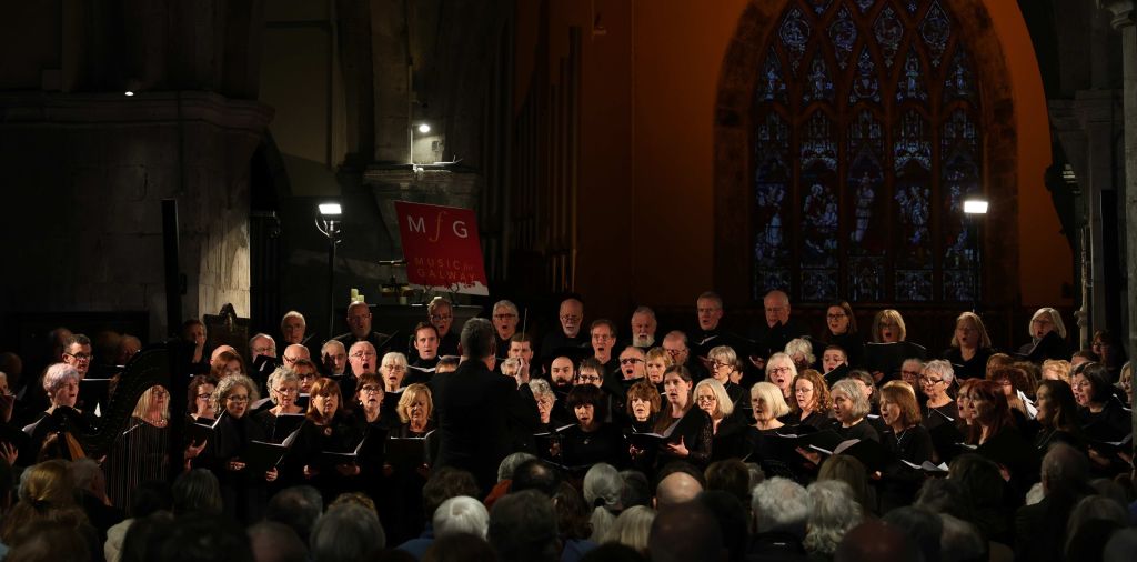 Image of a large choir singing in a church. They're dressed in black