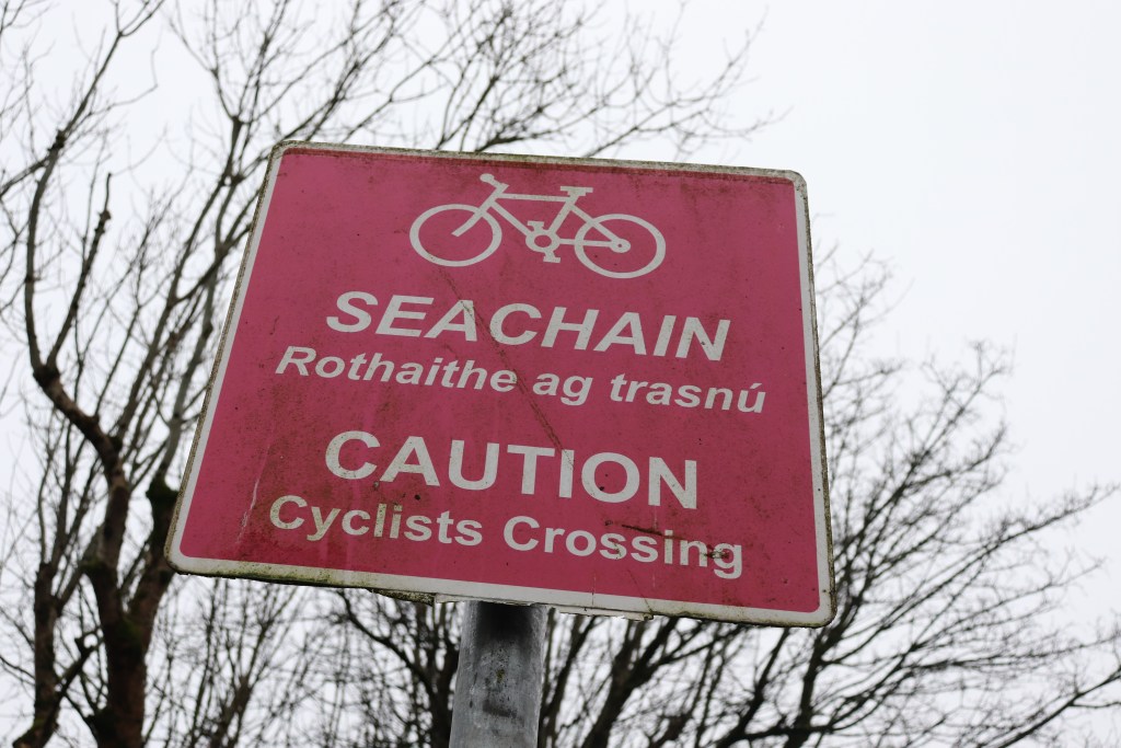 pink sign reading caution cyclists crossing