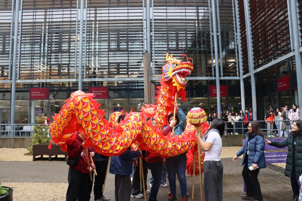 An image of people holding the Chinese Dragon outside the J. E. Cairnes Business School.