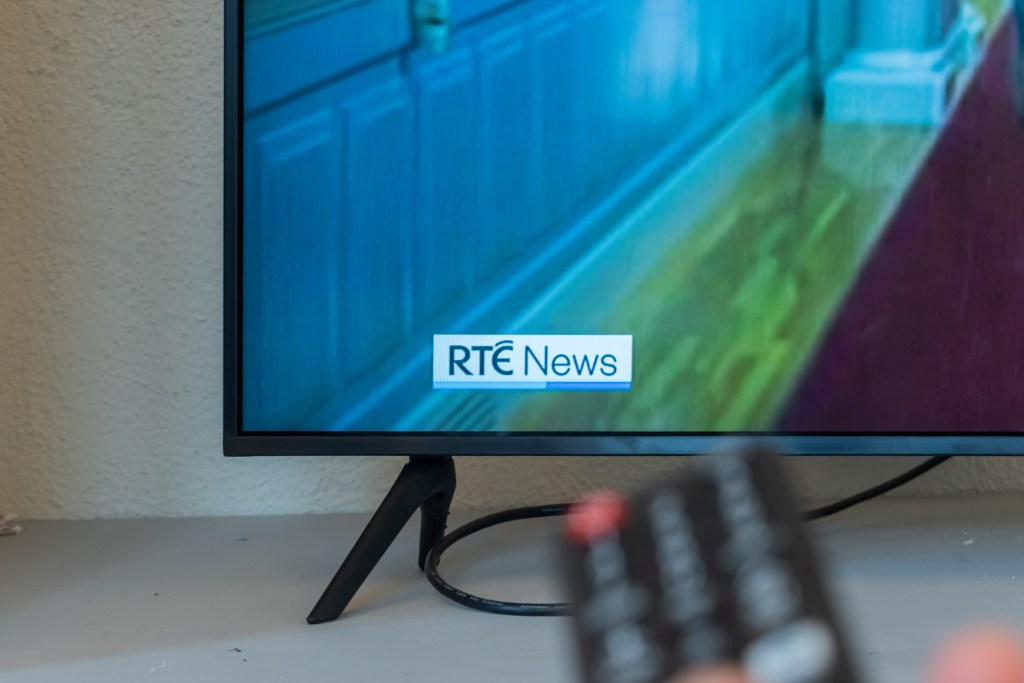 A remote pointing toward a television with RTÉ News on.
