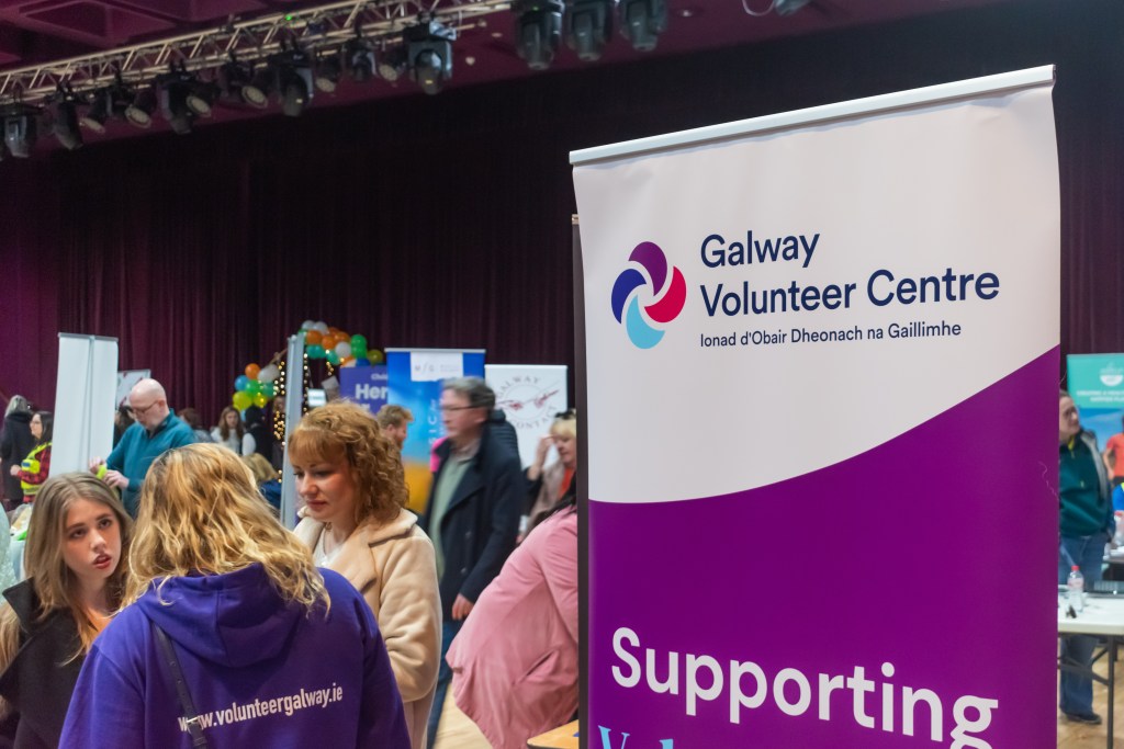 Crowd behind a banner featuring Galway Volunteer Centre's logo.