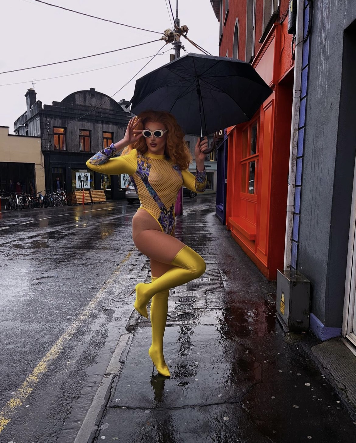 drag queen Devon Diva posing with umbrella outside of Bar Nova