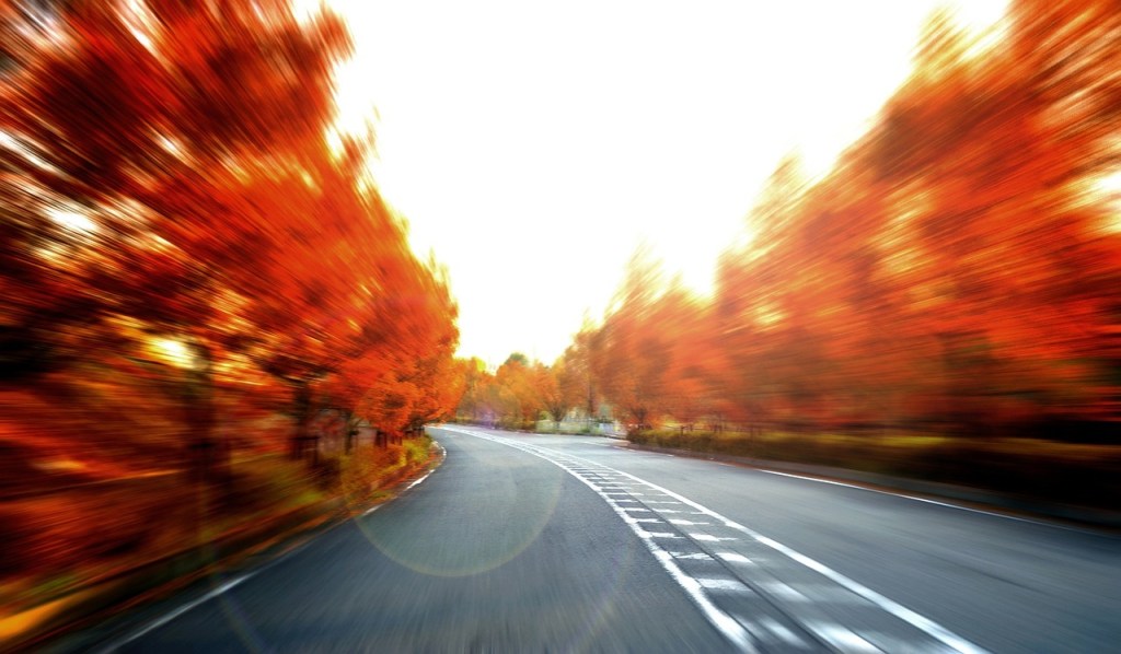 Speeding car travelling along autumn road
