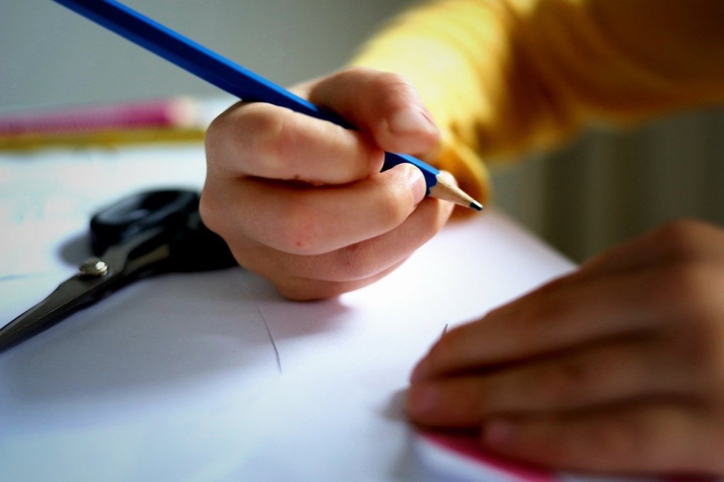 Close up of the hand of a primary school student writing with a pencil on paper